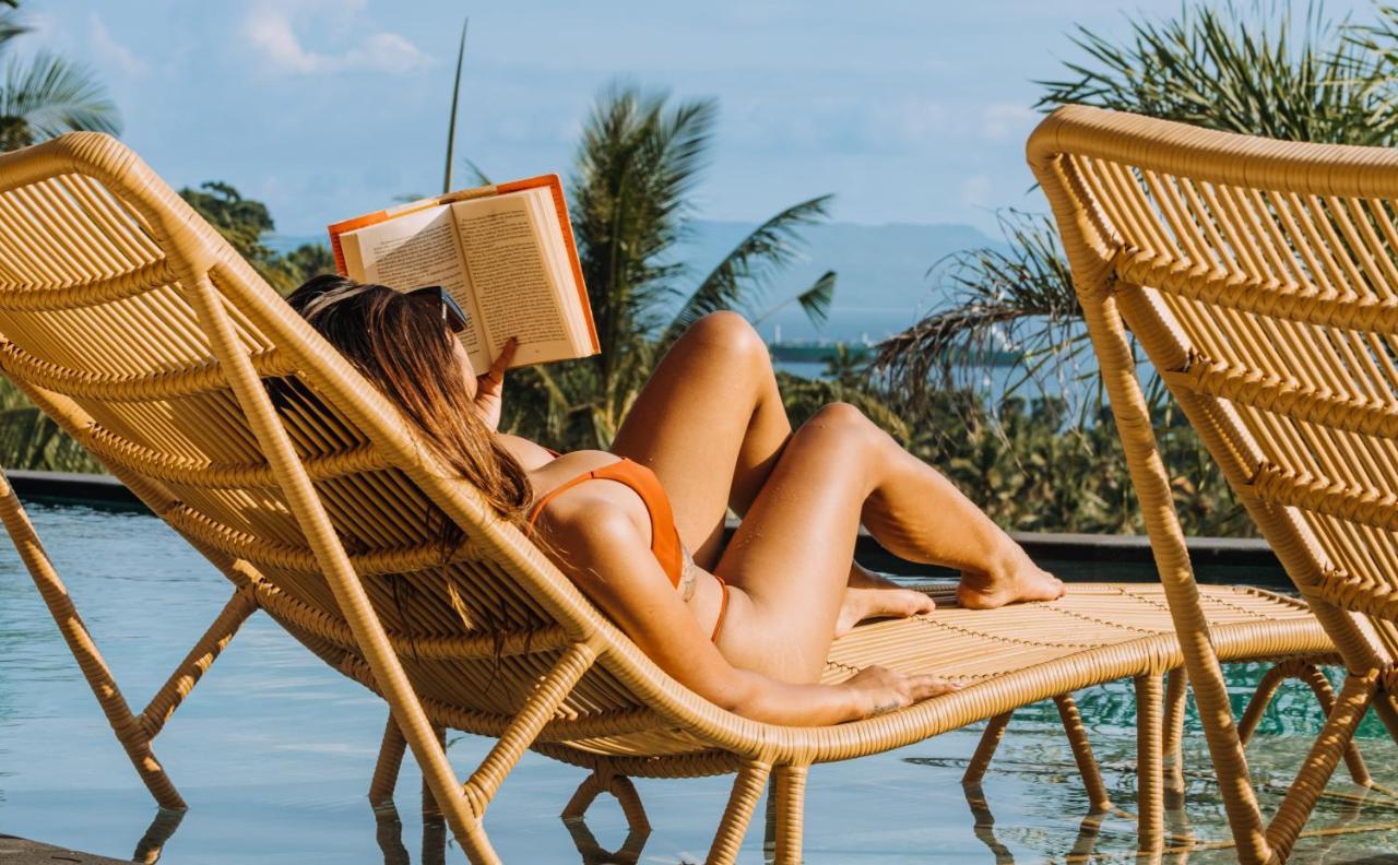 Neano Escape Hotel Manggis Kültér fotó A woman reading a book on a beach